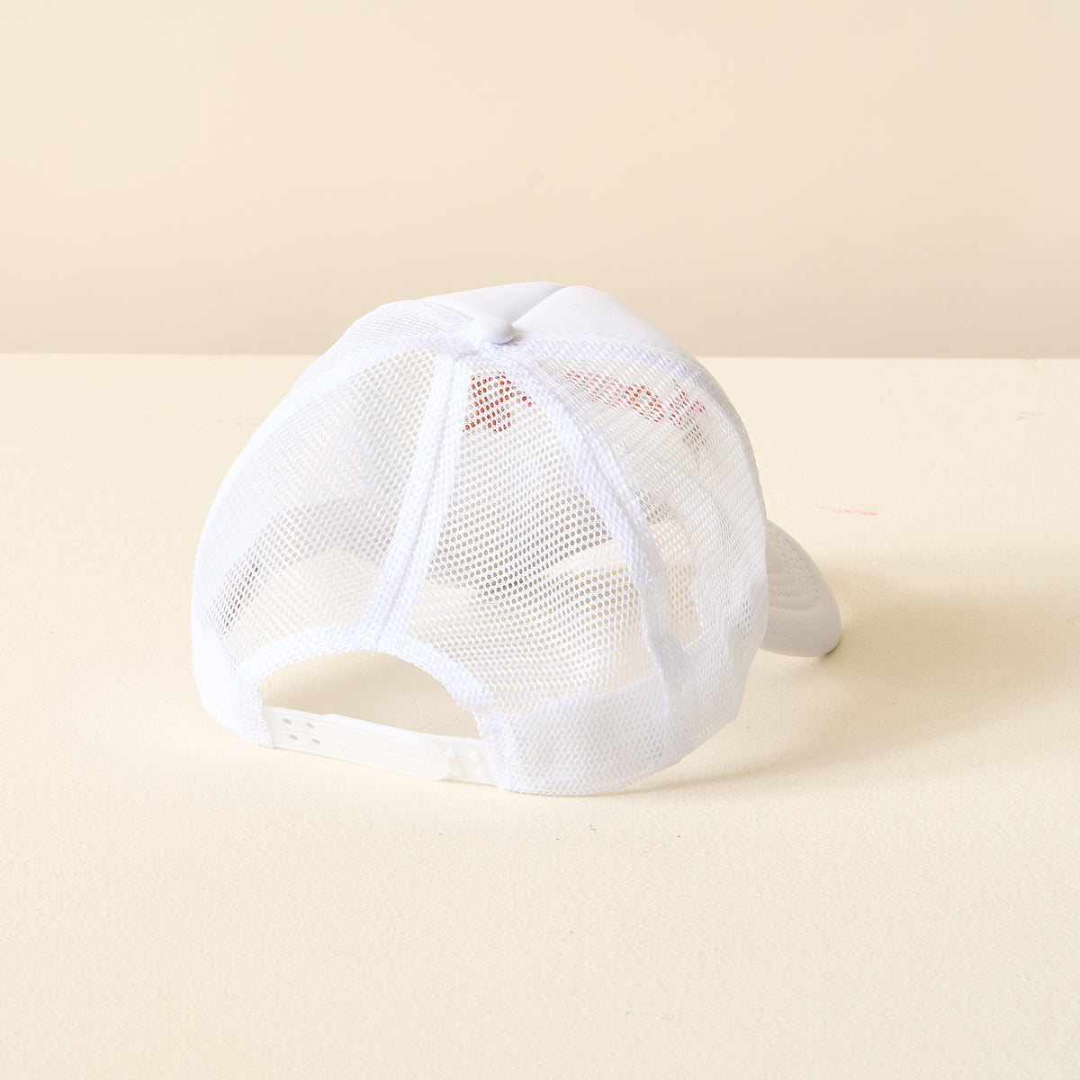 The Darling Effect’s Howdy Trucker Hat is displayed from the back, highlighting its white mesh panels and adjustable snapback closure, set on a light-colored surface against a plain background.