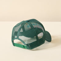The Darling Effect's Take it Easy Trckr Hat is displayed from the back, showing its adjustable snap closure and curved brim. The trendy green mesh hat rests on a light-colored surface with a plain background.