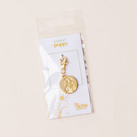 The August Jewelry Birth Flower Charm Gold by the-darling-effect features an engraved poppy flower on a gold charm with a clasp, attached to an AUGUST card, and packaged in a clear plastic bag.