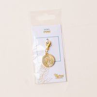 The June Jewelry Birth Flower Charm Gold by the-darling-effect features an engraved rose on a gold charm, attached to a "June rose" card and packaged in a clear plastic sleeve with a cream background.