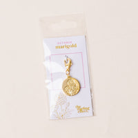 The-darling-effect’s October Jewelry Birth Flower Charm Gold features an engraved marigold on a white “October marigold” card, floral illustration, and brand logo, all packaged in a clear plastic bag.