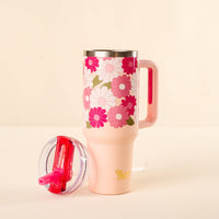 The Daisy Craze Hot Pink 40 oz Lifestyle Flip Straw Tumbler by the-darling-effect, featuring pink and white floral designs, sits on a light surface. Its leak-resistant flip straw lid with a pink attachment is placed beside it.