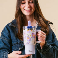 A woman smiles with her eyes closed while holding the-darling-effect's Bouquet Beauty Purple 20 oz Lifestyle Flip Straw Tumbler.
