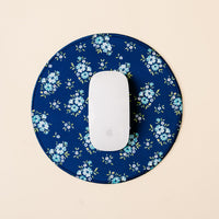 The Endless Daydream Navy Chic Clicks Mouse Pad by the-darling-effect, featuring light blue flowers, sits beneath a white wireless mouse, adding stylish flair to your workspace on a light beige background.