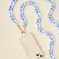 The Darling Effect’s Tri Cool Hold the Phone Crossbody Chain in blue, purple, and white pairs with a cream phone case with wavy edges for a trendy, hands-free way to carry your device anywhere.