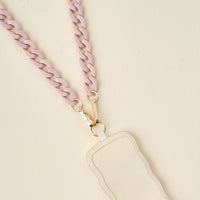 The Darling Effect Duo Lilac Hold the Phone Crossbody Chain features a chunky pastel lilac chain with gold clasps, attached to a blank off-white badge holder, styled as a hands-free phone accessory on a light cream background.