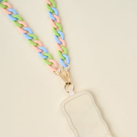 The Darling Effect’s Tri Lively Hold the Phone Crossbody Chain with pastel pink, blue, and green links clips to a beige, wavy-edged badge holder with gold clasps and is displayed on a light cream background.
