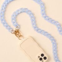 The-darling-effect's Marble Sky Blue Hold the Phone Crossbody Chain, featuring gold clasps, is paired with a cream wavy-edged phone accessory and displayed on a light beige background.