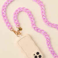 The-darling-effect’s Marble Violet Hold the Phone Crossbody Chain, featuring thick pastel pink marble links and gold hardware, is paired with a cream phone case with wavy edges and displayed on a light, neutral background.
