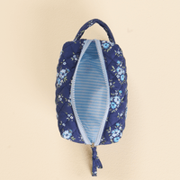 The Endless Daydream Navy Essentials Quilted Cosmetic Pouch by the-darling-effect features a quilted navy floral design, light blue zipper and handle, and reveals a blue and white striped wipeable interior against a light beige background.