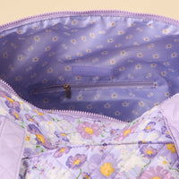 A close-up of the Bouquet Beauty Purple On-the-Go Quilted Weekender Bag by the-darling-effect, showing its zippered inner pocket and a lining with small white and yellow flowers in a floral pattern.