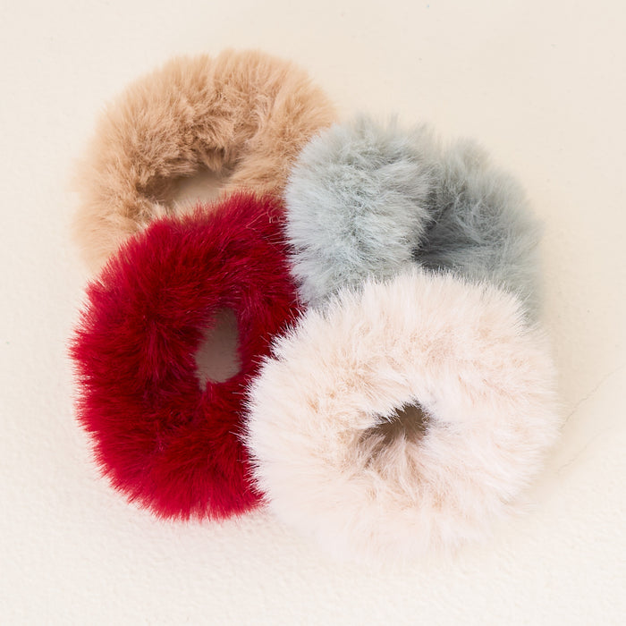 The Darling Effect Chill Faux Fur Scrunchie Set features four fluffy scrunchies in beige, grey, red, and off-white, clustered on a light background for a luxurious hair accessory upgrade.