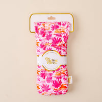 The Paradise Palms Sunglasses Case by the-darling-effect features a quilted design with pink, orange, and red tropical leaves, shown in branded packaging against a light beige background.