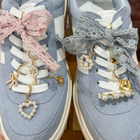 The Stardust Dazzle Shoe Charm Pack by the-darling-effect features gold and pearl heart, key, and flower charms to adorn your sneakers with elegance. Perfect for styling light blue kicks with white soles, laces, pink accents, and gray lace bows.