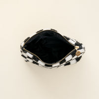A compact Check Black Teddy Pouch by The Darling Effect, featuring a black and white checkered pattern and a gold zipper, is shown open from above to reveal its black inner lining—ideal for organizing your purse.