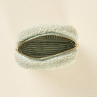 The Square Dainty Floral Sage Teddy Pouch by the-darling-effect is shown from above with its zipper open, revealing a striped fabric lining inside the light green sherpa pouch.