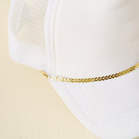 The Darling Effect's Gold-Leaf Chain Trucker Hat Chain is a white mesh trucker hat accessory with a shiny gold metallic chain above the brim, shown against a light beige background.