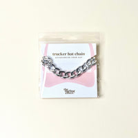 The Darling Effect’s Acrylic Link Silver Trucker Hat Chain features metallic links, comes attached to a card, and is packaged in a clear bag—perfect for adding style to any hat.