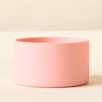 The Darling Effect Pink Tumbler Silicone Boot sits on a pale yellow surface against a cream background, providing a stylish no-slip grip and sturdy tumbler protection in one.