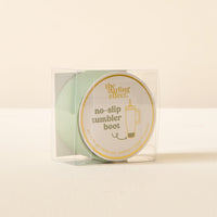 The Sage Tumbler Silicone Boot by The Darling Effect is light green, comes in a clear plastic box with a gold-bordered label that reads "the darling effect. no-slip tumbler boot" and shows an illustrated tumbler.