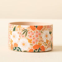 The Darling Effect's Sweet Meadow Orange Tan Tumbler Silicone Boot features a round, light pink design with colorful floral patterns—white, orange, and pink flowers with green leaves—perfect as a charming tumbler accessory or paired with a No-Slip Tumbler Boot.