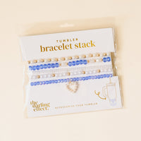 The On Cloud Nine Tumbler Bracelet Stack by the-darling-effect features pearl, gold, and blue crystal beads with a heart charm—perfect for 40 oz tumblers. Comes in plastic packaging with the-darling-effect branding.