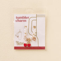 Add flair to your personalized tumbler with the-darling-effect Cherry Tumbler Charm, featuring red cherry, gold bow, white flower, and gold heart accents—cute tumbler accessories on a card labeled Tumbler Charm and The Darling Effect.