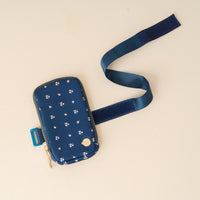 The Pretty Posies Teal Tumbler Fanny Pack by The Darling Effect is a small, water-resistant floral pouch with gold accents and a long blue Velcro strap, displayed on a light-colored surface.