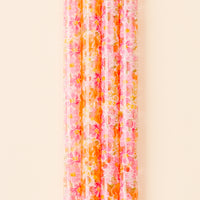 A close-up of the-darling-effect’s Secret Garden Pink 40 oz Tumbler Straw Set, featuring pink and orange floral patterns, arranged vertically against a light beige background.