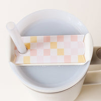 Rectangular peach, pink, and yellow checkered Check Peach Tumbler Lid Tag attached to the straw and lid of a Stanley Quencher 2.0 tumbler.