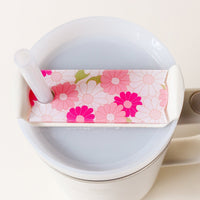 A white straw extends from a Stanley Quencher 2.0, adorned with The Darling Effect’s Daisy Craze Hot Pink Tumbler Lid Tag—featuring playful pink and white daisies for a stylish, personalized touch to your tumbler lid collection.