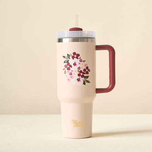 The Buds & Bloom Blush 40oz Take Me Everywhere Tumbler by The Darling Effect is a pink floral tumbler with a maroon handle, straw, and gold “the darling effect” text on the bottom.