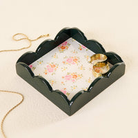 The Endless Daydream Cream Scallop Trinket Tray by the-darling-effect holds two gold rings. Its floral pattern adds elegance, while a gold chain necklace rests beside it on a cream-colored surface.