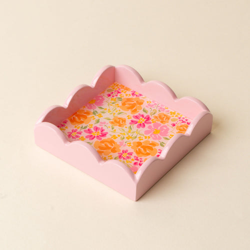 The Secret Garden Pink Scallop Trinket Tray by the-darling-effect is a pink, square tray with scalloped edges and a floral-patterned base featuring orange, yellow, and pink blooms on a light cream background—ideal for organizing jewelry or displaying accessories.