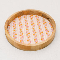 The Petal Parade Pink Large Round Wood Enamel Tray by the-darling-effect features a floral and striped base in pink and orange, making it a charming bamboo serving tray for any occasion.