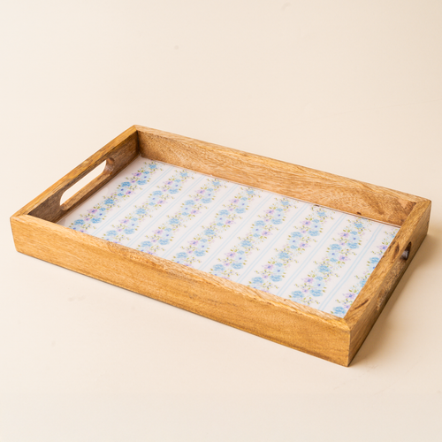 The-darling-effect's Petal Parade Blue Rectangle Wood Enamel Tray features cut-out handles and a blue and yellow floral pattern on white, making it a charming addition to your serving collection.