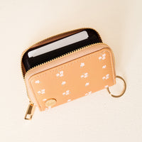 The Darling Effect’s Pretty Posies Mustard Zip Around Wallet features a compact design with white floral patterns, a gold zipper, and a convenient keyring. When opened, it reveals multiple card slots inside.