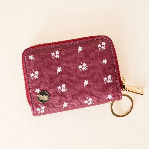 The Darling Effect’s Pretty Posies Plum Zip Around Wallet features card slots, a gold zipper, keyring, and a white floral pattern on maroon, displayed against a light background.