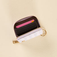 The Petal Parade Blue Zip Around Wallet by the-darling-effect is a small, compact, and stylish accessory featuring a floral pattern, gold zipper, and keyring. Shown open on a beige surface, it reveals several interior card slots with a pink card visible at the front.