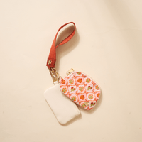 The Darling Effect Patchwork Pumpkins Dynamic Duo Pouch Wristlet features two small zippered pouches—one plain white, one with a colorful pumpkin pattern—attached to a luxe red wristlet with gold clasp for hands-free convenience.