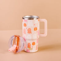 The Darling Effect’s Ghost Party 20 oz Lifestyle Flip Straw Tumbler, adorned with cute ghost and pumpkin designs, sits beside its transparent lid and pink straw on a beige background.