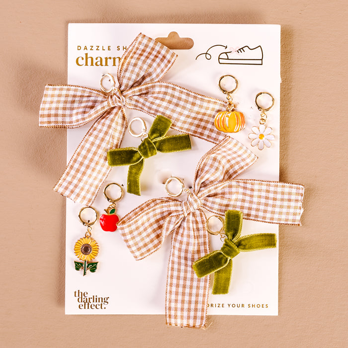 The Darling Effect’s Hayride Honey Dazzle Shoe Charm Pack features two large plaid bows, two small green bows, and four sneaker charms (pumpkin, daisy, sunflower, red apple)—stylish accessories to personalize your shoes.