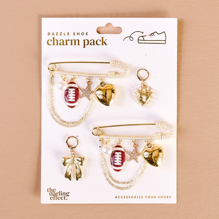 The Darling Effect’s Tailgate Time Dazzle Shoe Charm Pack features two gold safety pin-style sneaker charms with pearl chains, a red football, gold heart, star, pearl, heart pendant, and bow—fun accents to upgrade your footwear.
