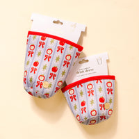 Two Oh So Orchard Sip Savvy Drink Sleeves by The Darling Effect, featuring red apples, bows, and florals on a light background, are displayed in packaging on a pale yellow surface—an adorable Starbucks cup accessory.
