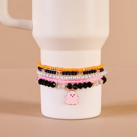 The Darling Effect’s Spook & Sparkle Tumbler Bracelet Stack, shown on a white 40 oz tumbler against a beige background, features pink, black, gold, pearl beads and a pink ghost charm for playful style.