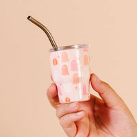 A hand holds The Darling Effect Ghost Party 2 oz Tiny Tumbler—a small pink Halloween cup featuring a ghost pattern and a silver straw.