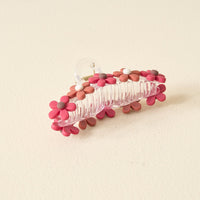 The Darling Effect's Burgundy Game Day Daisy Claw Clip features pink, red, and white floral accents—ideal for adding school colors to your outfit. Shown on a light beige surface.