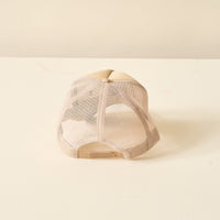 A Red Game Day Trucker Hat from The Darling Effect is placed upside down on a white textured surface, viewed from the back with its adjustable strap visible—perfect for showing team spirit on game day.