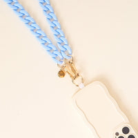 The Darling Effect’s Light Blue Game Day Phone Chains feature a cream-colored wavy-edged case paired with a chunky light blue strap and gold hardware—an eye-catching accessory for game day, shown on a light beige background.