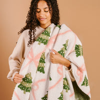 Cozy blanket draped over shoulders with green tree print and pink bow accents
